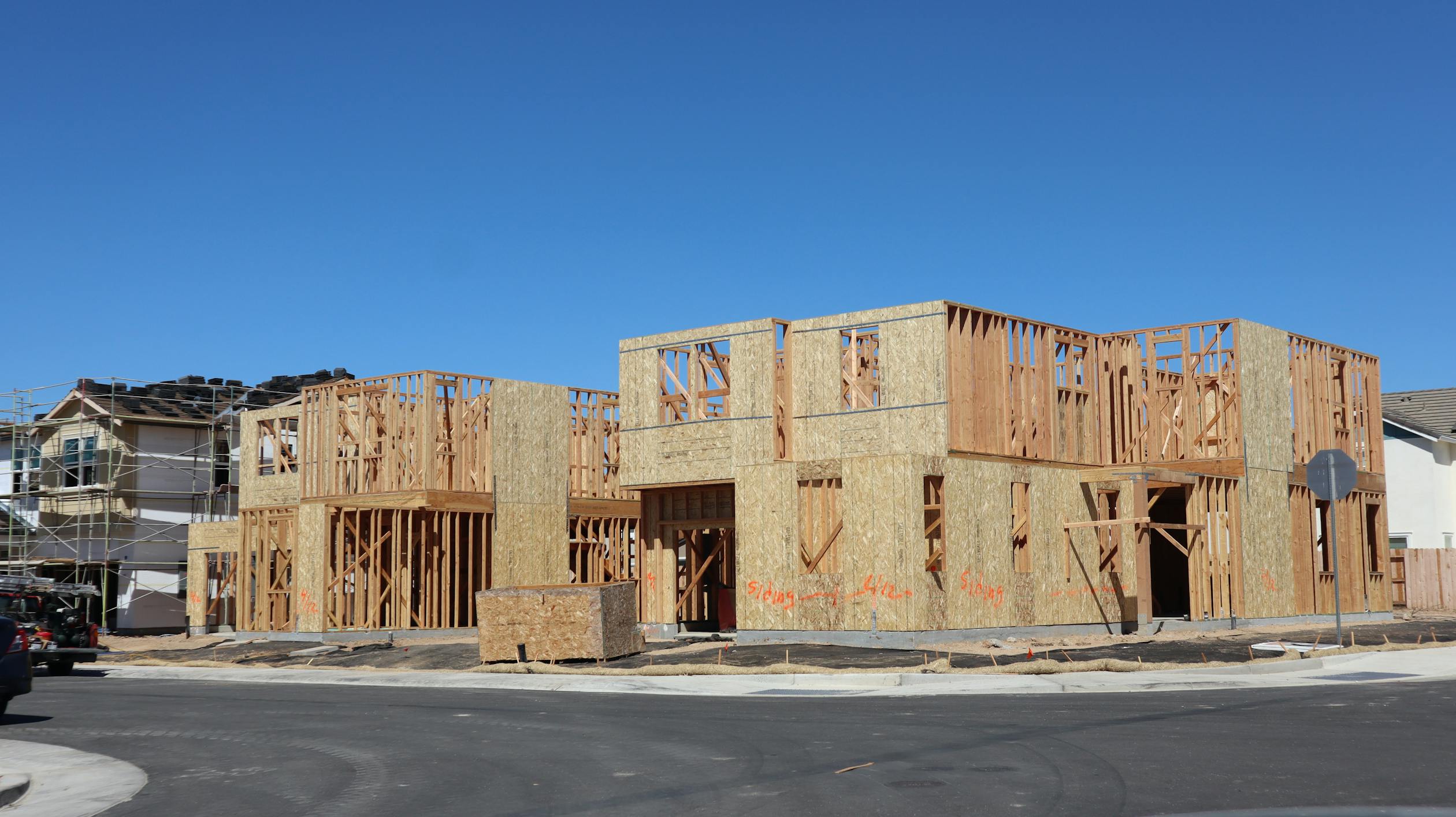 This image depicts a new home under construction with visible lumber framing, showcasing well-aligned beams, columns and joists.