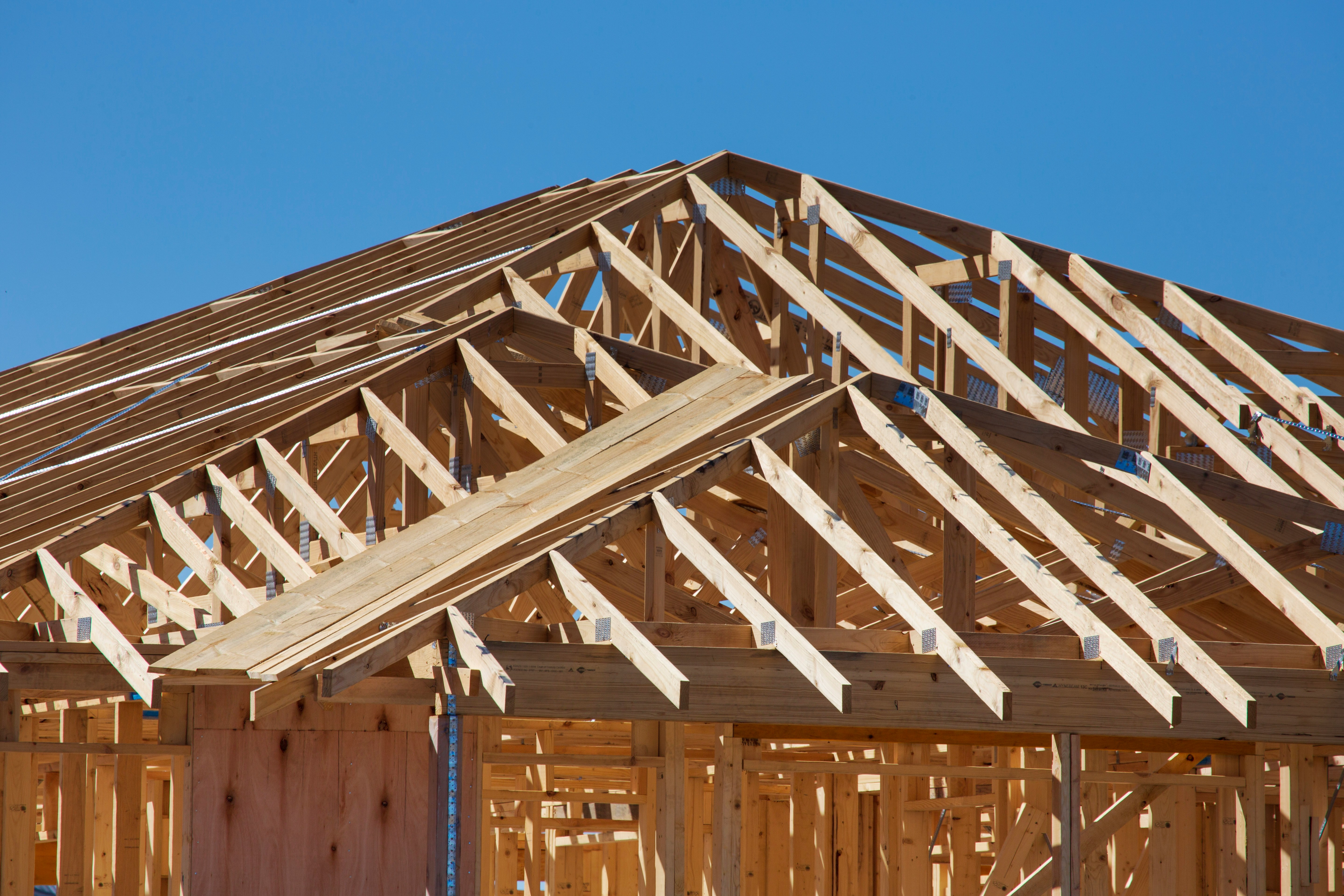This image depicts a residential building under construction, featuring exposed trusses. The trusses are visible supporting the roof structure.