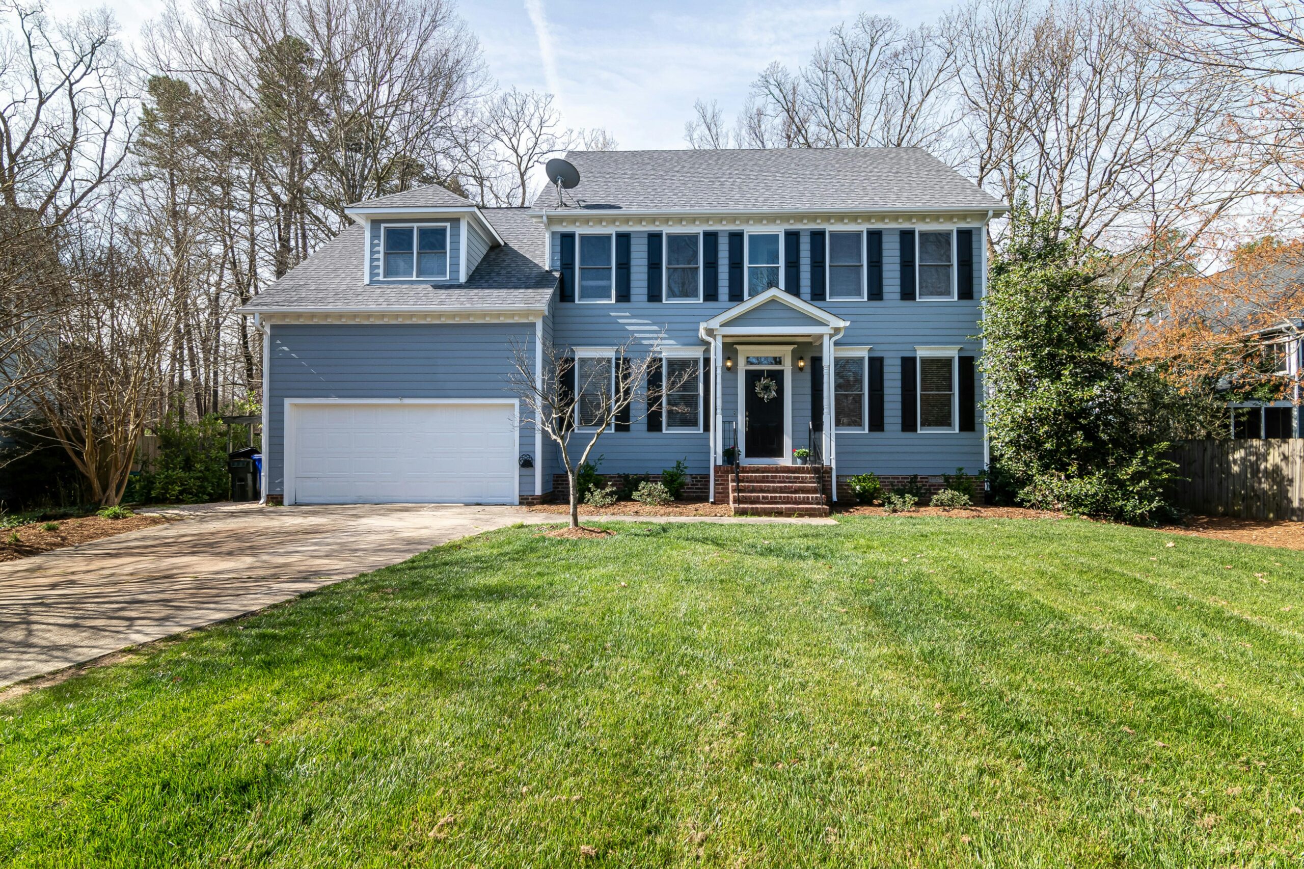 This image depicts a blue house with a black door that matches the black shutters. 