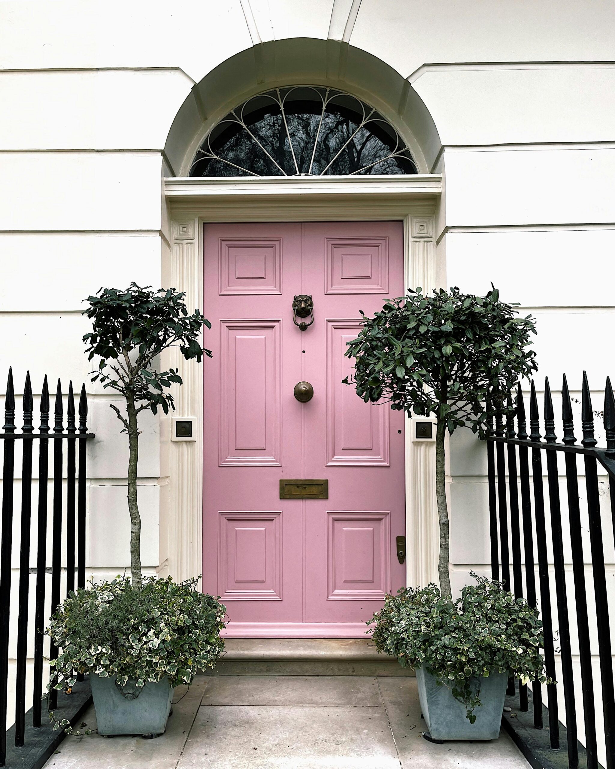 This image depicts a pink door against a white house. 