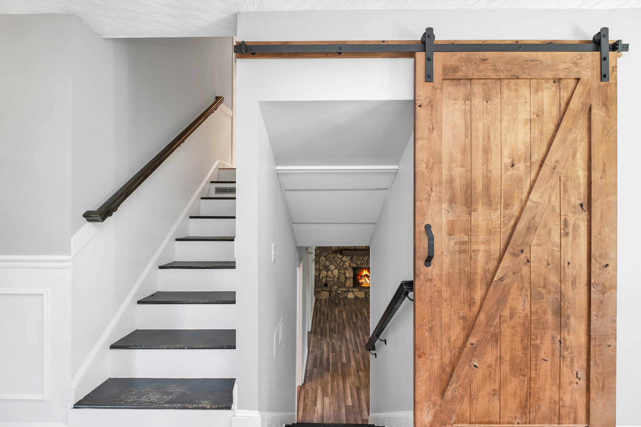 This image depicts a wooden barn door opening to a stairway. The stairway leads to a basement. 