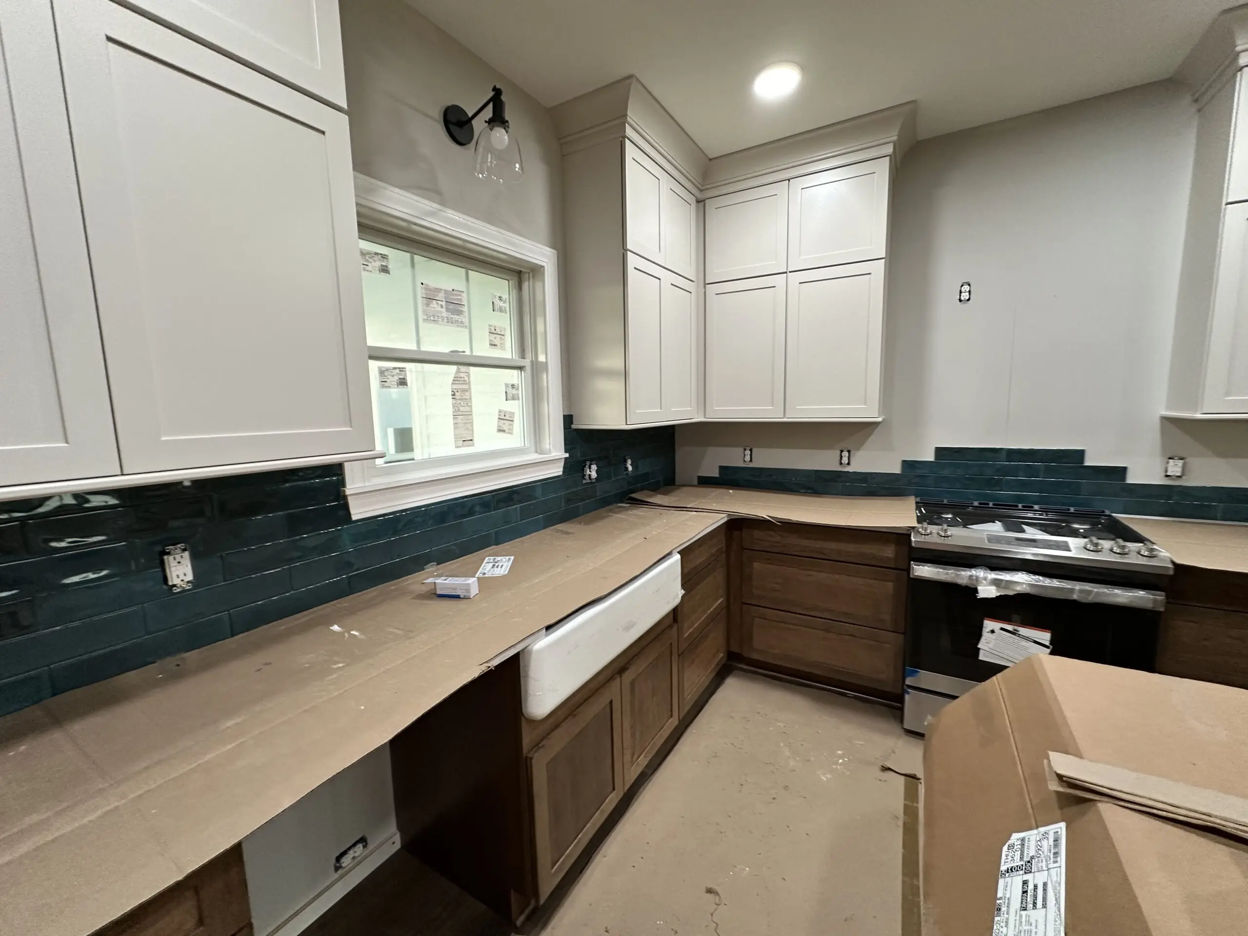 A modern kitchen under construction, with full overlay cabinets installed on the walls. 