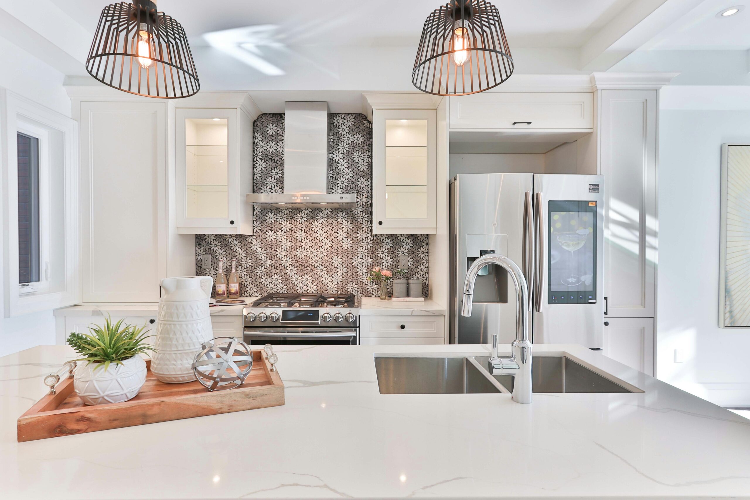 A bright, modern kitchen has a large island, sleek cabinets, stunning quartz countertops and stainless steel appliances.