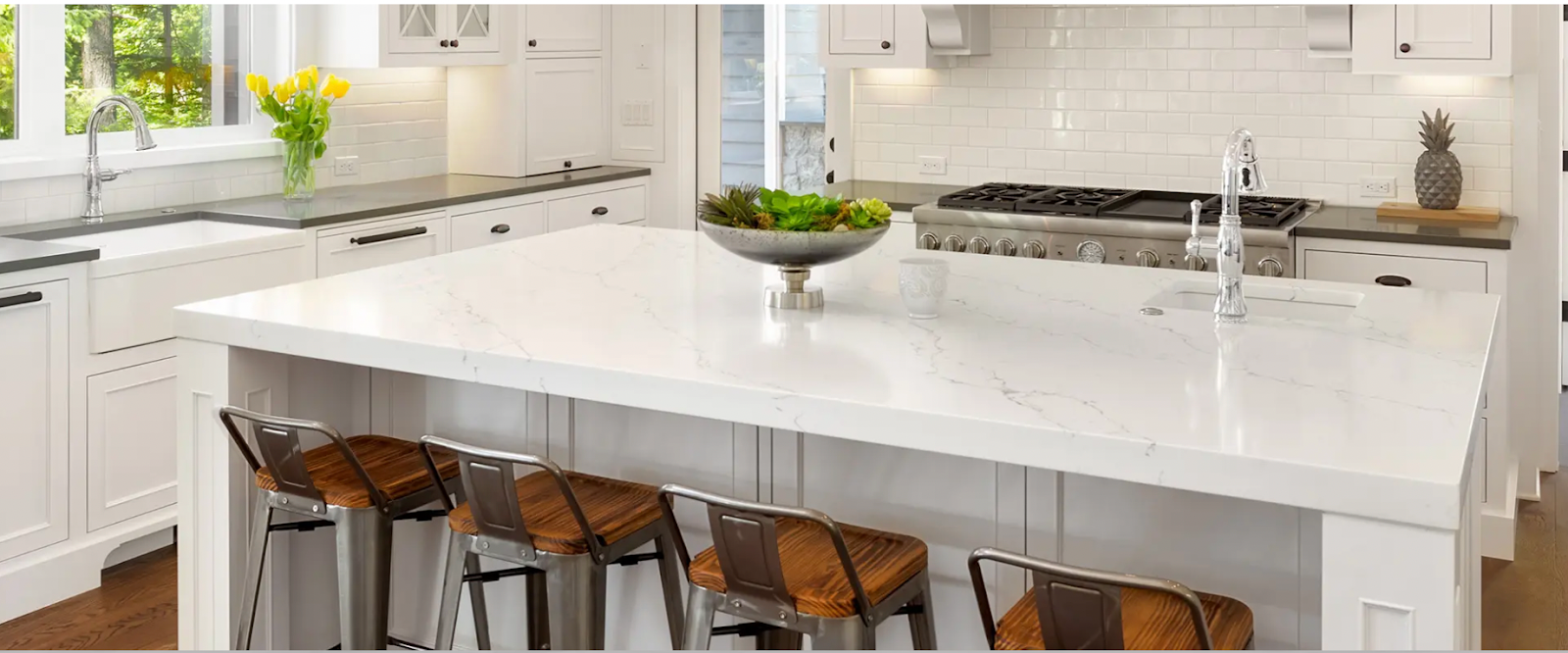 A modern kitchen has a beautiful quartz countertop paired with white cabinetry and stainless steel appliances.