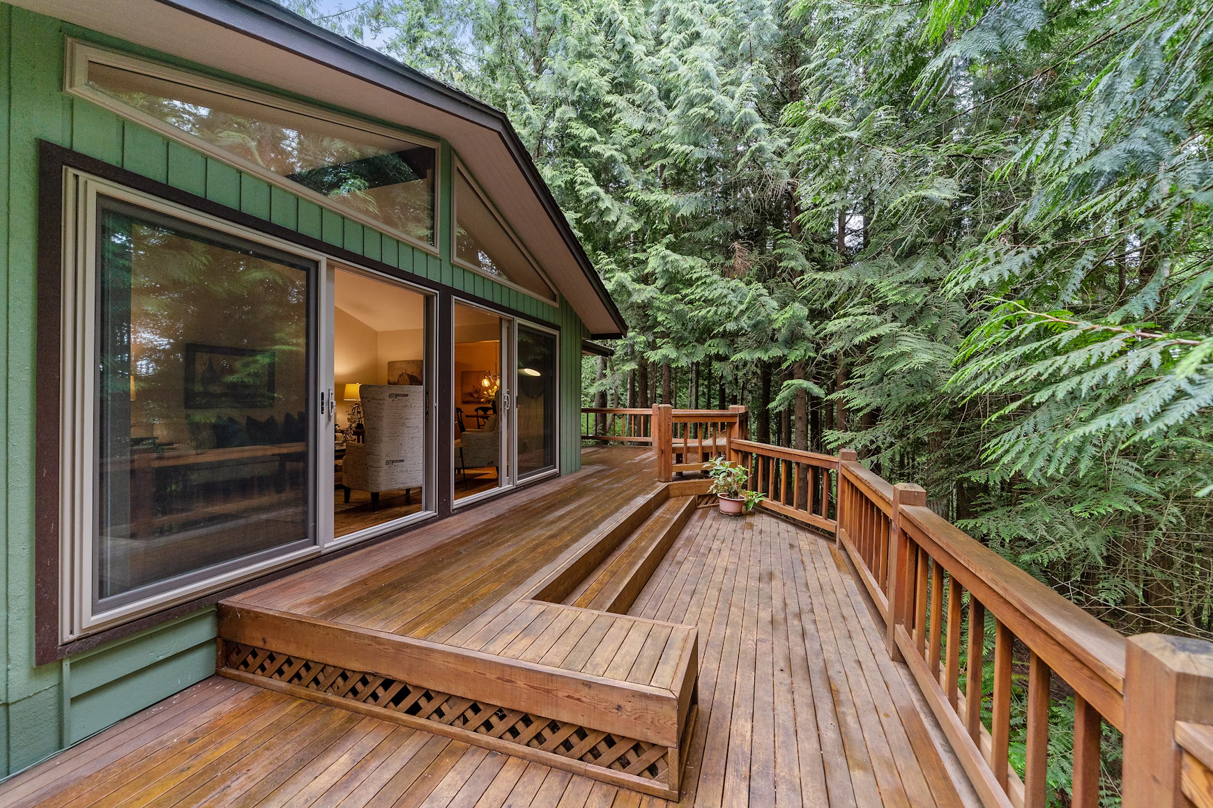 A home has a large back deck with pressure-treated wood for longevity and durability. The deck overlooks a wooded forest.