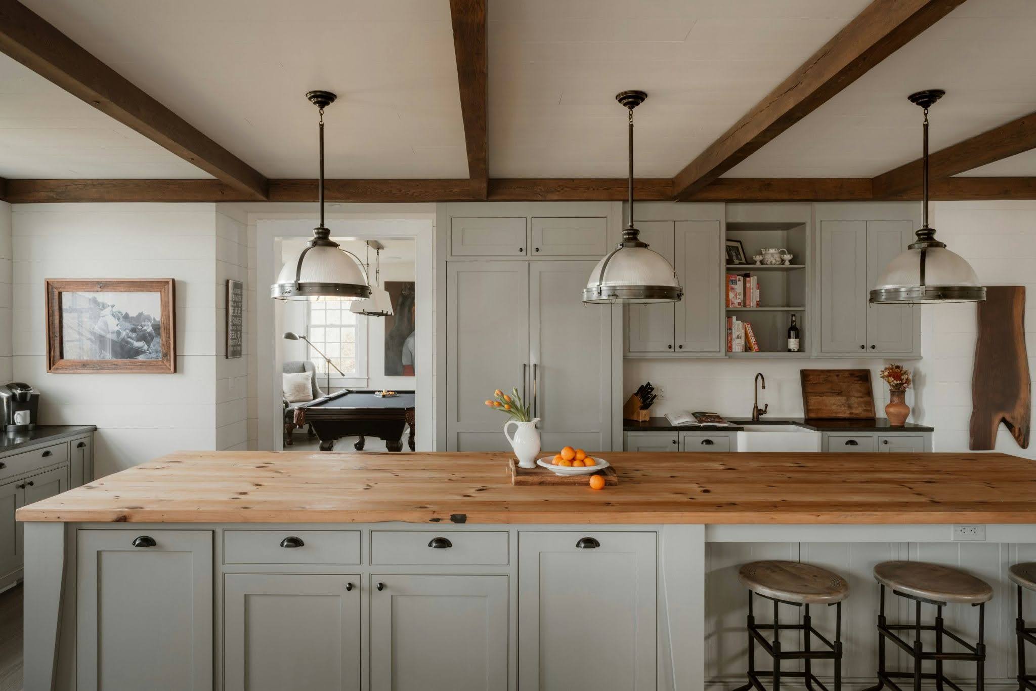 A farmhouse-style kitchen has exposed wood ceiling beams and a large butcher block island with natural wood knots.