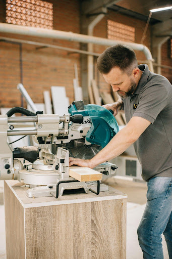 A professional cuts lumber with a Makita miter saw.