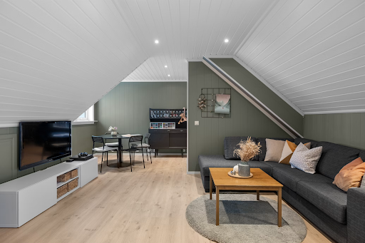 Cozy attic lounge area styled with a comfortable sofa, low coffee table and a mounted flat-screen TV in a converted roof space.